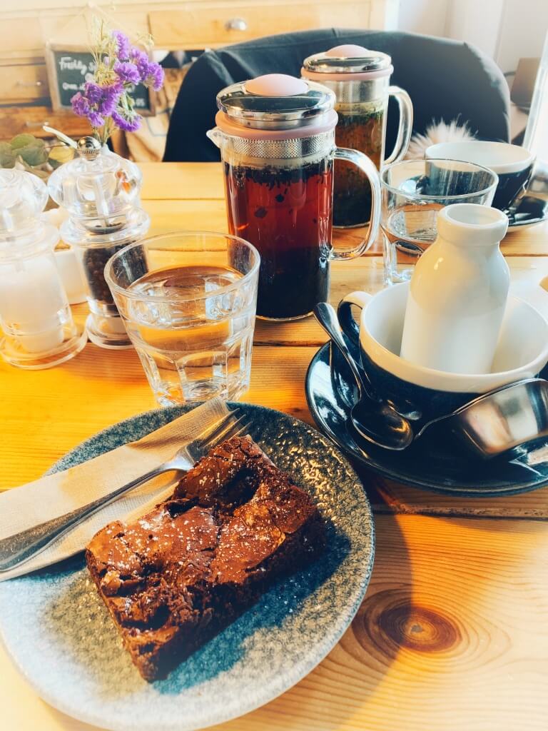chocolate brownie, glass of water and a tea infuser on a table at the Brew and Brownie cafe, York