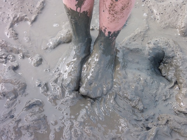 bare feet up the the ankles in wet mud