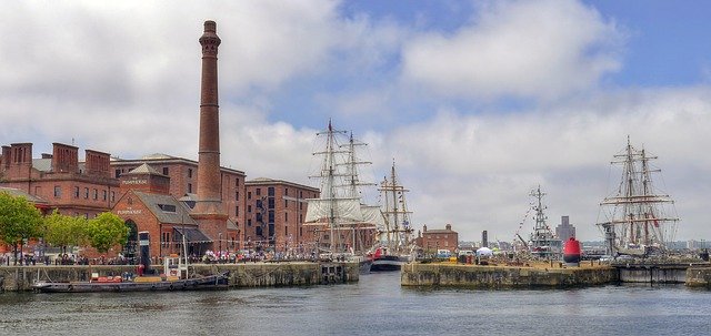 a view of the Albert Dock Liverpool, encompassing the Pump House Pub and 4 tall ships against blue skies
