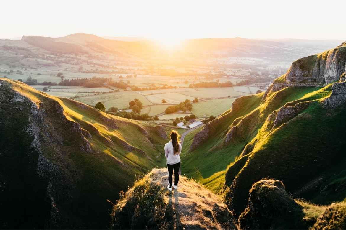 a girl standing at a high view point overlooking Happy Valley in the Peak District at sunset
